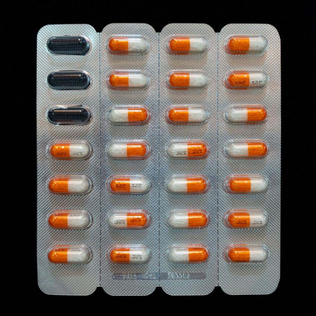 A close-up of capsules in their sealed blister packaging against a dark background.
