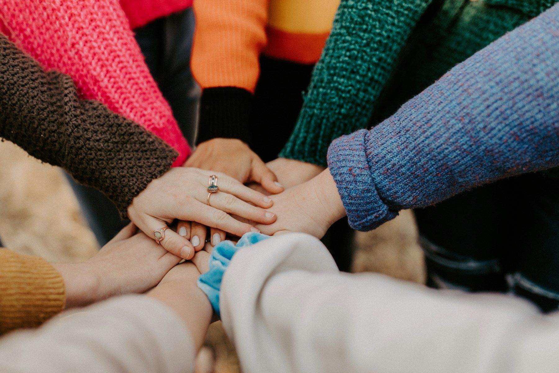 A group of people stacking their hands together in a gesture of teamwork.