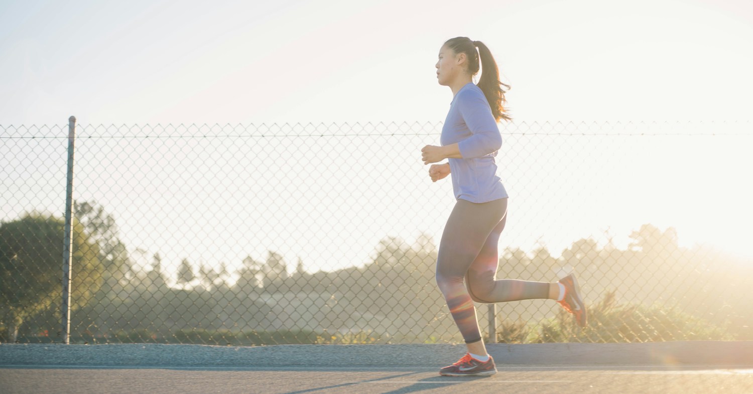 A woman running outdoors in the morning light.