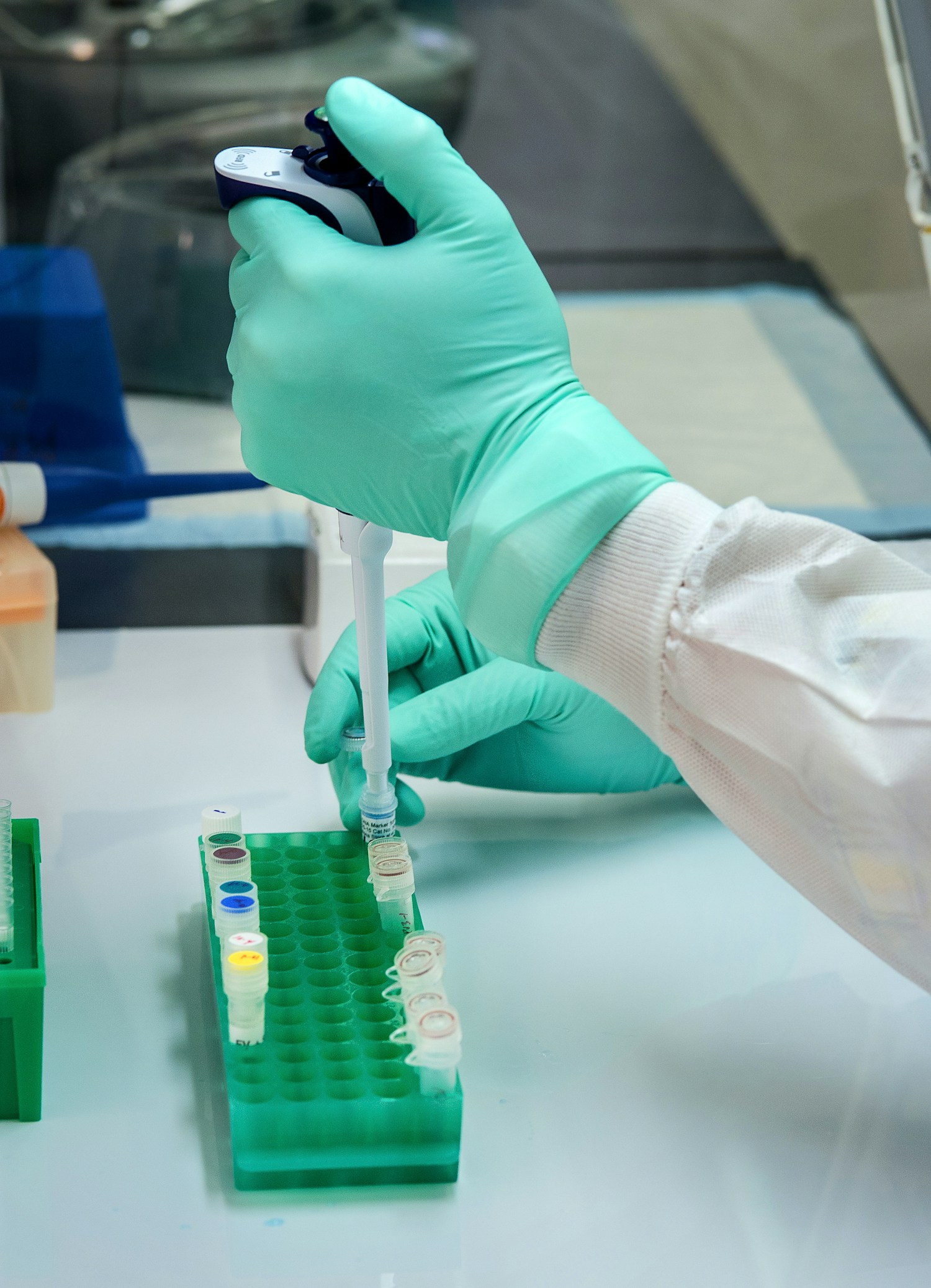 Gloved hands using a pipette in a laboratory.